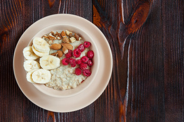 Delicious oatmeal with raspberry nuts and banana. Top view. Copy space.