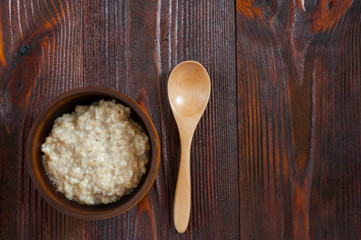 Tasty oatmeal in wooden bowl on table. Top view. Copy space.