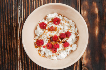 Cottage cheese with raspberries and honey in bowl. Top view.