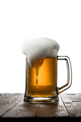 Frosty mug of light beer on wood table
