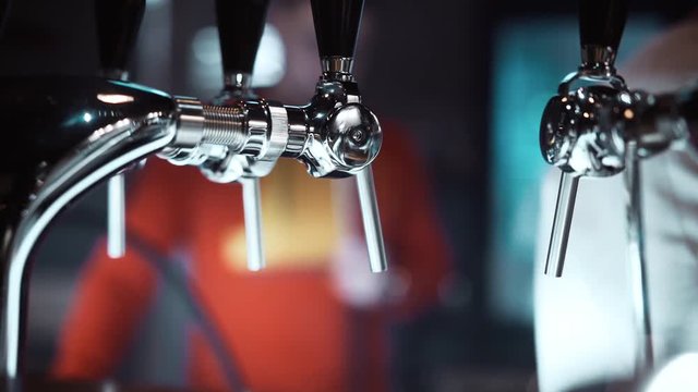 Close-up. Beer tap. Pouring beer in the bar. Compensatory tap for beer. Blurred bar background. Bar counter