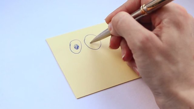 Female hand draws funny smiley face with pen close up. Motivational concept