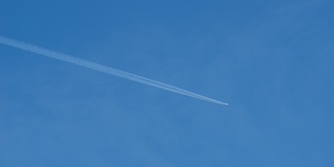 Plane flying on a blue sky, condensation line.