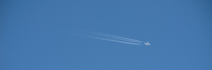 Plane flying on a blue sky, condensation line.