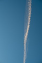 Plane flying on a blue sky, condensation line.
