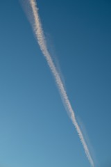 Plane flying on a blue sky, condensation line.