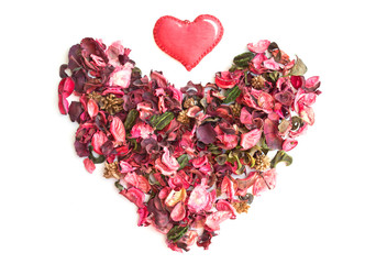 Heart made of dried rose petals and textile red heart on white background