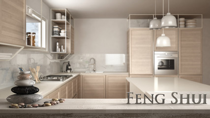 Wooden vintage table shelf with pebble balance and 3d letters making the word feng shui over blurred minimalist white and wooden modern kitchen, zen concept interior design