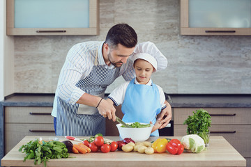 Father and son are cooking in the kitchen