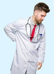 Young handsome doctor man wearing medical coat Suffering of backache, touching back with hand, muscular pain