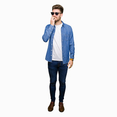 Fototapeta premium Young handsome elegant man wearing denim jacket looking stressed and nervous with hands on mouth biting nails. Anxiety problem.