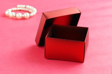 Empty red gift box with lid open on a pink background
