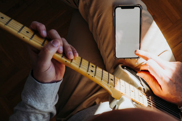 Man teaching himself to play guitar with smartphone