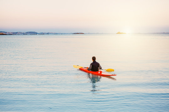 Kajak Fahrer padelt ins Meer hinaus bei Sonnenuntergang