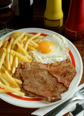Plato combinado con un Bisteck, un huevo frito y patatas fritas.