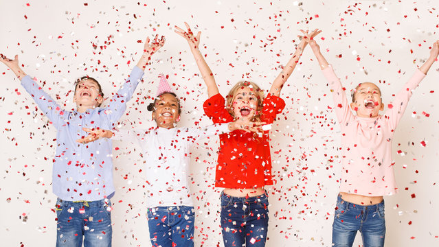 Happy children throwing confetti against light background