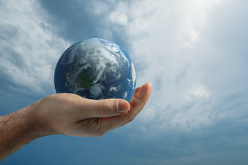 Globe in human hand against blue sky. Environmental protection concept.