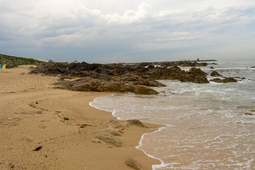 Rocks and yellow sand on atlantic beach. Porto, Portugal.