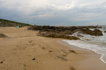 Rocks and yellow sand on atlantic beach. Porto, Portugal.