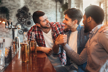 Male friends meeting in pub, drinking beer