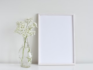 Minimalistic interior, white frame mockup with glass vase and flowers on white background.