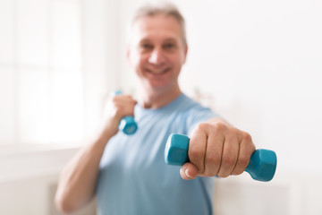 Mature man exercising with dumbbells at home