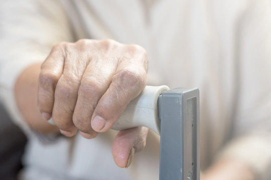 Parkinson's disease medical healthcare concept. Hand of older patient female holding walking stick in geriatric center or nusring home.