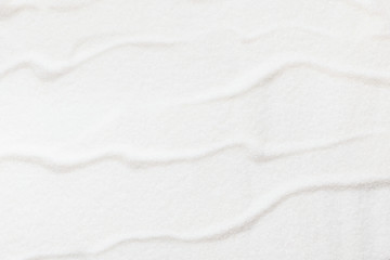 Wavy pattern on white sugar background, copy space