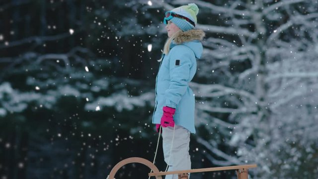 CINEMAGRAPH - SEAMLESS LOOP. Cute little girl child preparing for a sledge ride down the hill. Child plays outdoors in snow, winter fun. 4K UHD