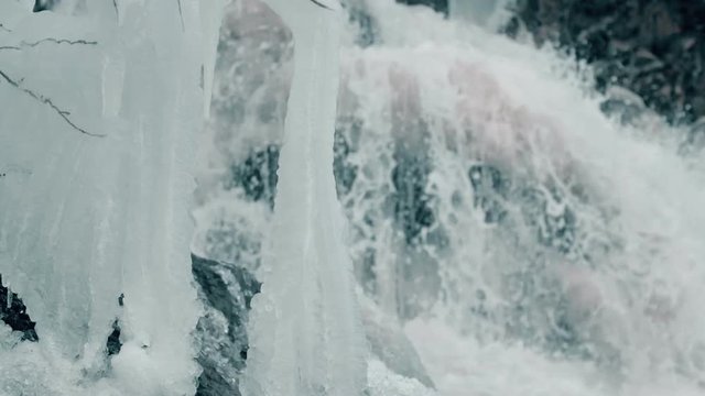 Close up of crystal waterfall water with ice in slow motion.
