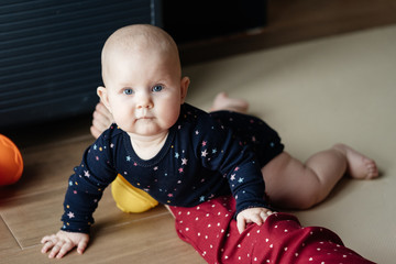 Portrait of a baby crawling on the floor and looking into the camera. The development of one year old baby.