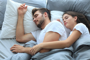 Happy couple sleeping in a comfortable bed at home.