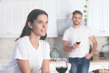 Pretty young woman drinking some wine at home in kitchen.