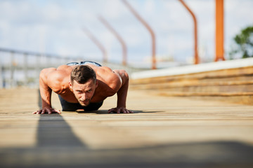 Athletic man doing pushups during outdoors workout