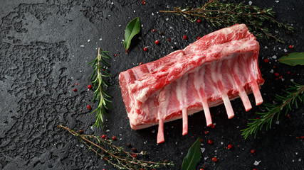 raw fresh rack of lamb with green herbs.