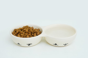 Ceramic bowl with dry food and water for cats. Close-up. White background.