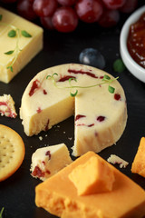 Cheese platter served with grapes, ale chutney, honey, crackers on stone board. Brie, cheddar, red leicester, wensleydale cranberries, blue stilton.