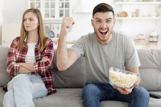 Young Man Watching Super Bowl And Supporting His Favorite Team While Girl Is Upset Because She Does Not Want To Watch Match