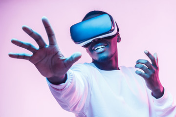 African american man in vr glasses, playing video games with virtual reality headset, trying to...