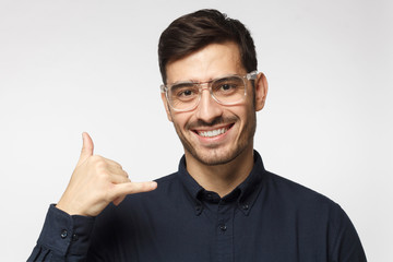 Call me baby. European guy isolated on gray background, showing gesture as if asking to dial him, looking confident. Technical support concept