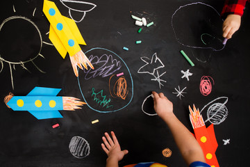 the children draws a rocket and space on a blackboard. preschool Child in creativity in the home.