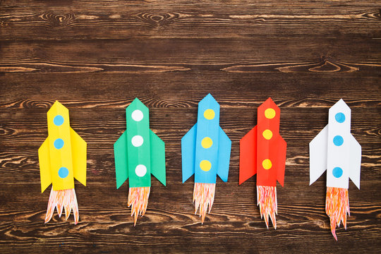 top view of flying multi-colored rockets from paper on a wooden background