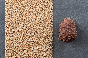Peeled pine nuts and pine cones on a gray stone background.