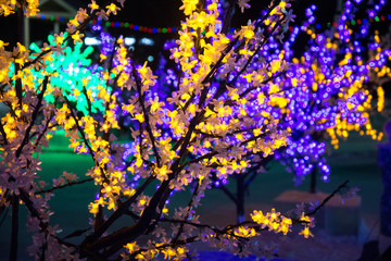 Beautiful glow flower with neon lamp light decorate on tree beside road