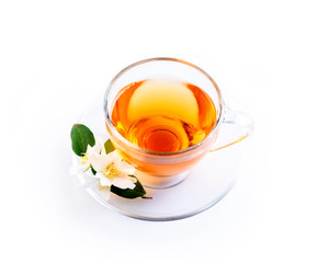 Asian green tea with jasmine flower in transparent teacup isolated on white background with reflection.