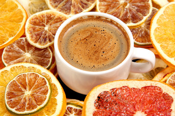 Dried slices of various citrus fruits and black coffee in a white Cup