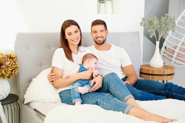 Happy young family relaxing in bed with their baby girl