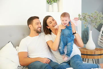 Happy young family relaxing in bed with their baby girl