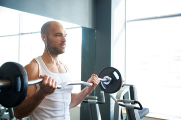 Sporty man doing exercises with dumbbell in the gym.