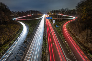 Fototapeta na wymiar Autobahnausfahrt und Autobahnauffahrt bei Nacht mit Lichtstreifen